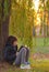 Teenage girl reads the book under the willow tree