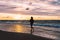 Teenage girl running barefoot on a sandy beach at sunset - a silhouetted photo of a young woman against the sky