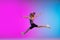 Teenage girl running, jogging against gradient pink-blue neon studio background in motion