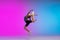 Teenage girl running, jogging against gradient pink-blue neon studio background in motion