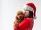 A teenage girl in a Santa Claus hat and a red Christmas sweater holds a miniature poodle in her arms. The concept of Christmas and