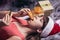 A teenage girl in a Santa hat eats Christmas cakes lying on the carpet