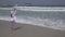 Teenage girl shoots on smartphone the sea waves on Public Jumeirah Open Beach on the coast of the Persian Gulf, Dubai