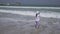 Teenage girl shoots on smartphone the sea waves on Public Jumeirah Open Beach on the coast of the Persian Gulf, Dubai