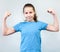Teenage girl shows strength tensing muscles on a grey background. Caucasian child in blue t-shirt