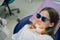 a teenage girl sits in a chair in a dental office. regular preventive visits