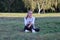 Teenage girl sits on a grass on the meadow