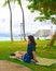 Teenage girl sitting alone at empty Waikiki park by  ocean