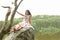 Teenage girl sitting on rock above river