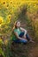 Teenage girl sitting among sunflowers