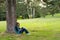 Teenage girl sitting under the tree and reading book in forest