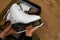 A teenage girl is sitting on the wooden floor in her room. She holds a brand new figure skate in her hands. Pair of white figure