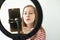 Teenage girl social media blogger recording video speaking looking at smartphone on tripod with ring light