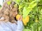 a teenage girl is standing near a lemon tree she is holding a lemon in her hands she is sniffing it she is going to make