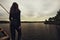 a teenage girl stands alone on the pier at the pier trying to cope with anger and find strength in the evening rested