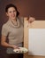 Teenage girl stands behind easel with empty sheet