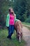 Teenage girl stands with a little horse on the country roadside