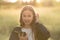 a teenage girl stands with a phone in nature.