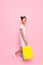 Teenage girl in stylish dress with packages in hand makes a purchase, on a pink background