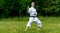 Teenage girl training karate kata outdoors, performs soto uke or outside block in kakutsu dachi stand