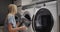 A teenage girl transfers clean clothes from the washing machine to the dryer