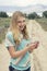 Teenage girl using cellphone walking down a country dirt road