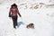 A teenage girl walking a puppy in a cold winter landscape