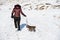 A teenage girl walking a puppy in a cold winter landscape