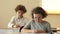 Teenage girl wearing glasses laughs cheerfully at school during a lesson. The schoolgirl has a fan sitting at her desk