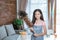 Teenage girl wearing a smiling apron while holding a feather duster looking at the camera