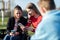 Teenage Girl In Wheelchair With Friends Looking At Social Media On Mobile Phones In Park