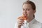 A teenage girl in a white shirt puts a slice of pizza to her mouth and takes a bite, looks at the camera