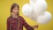 Teenage girl at yellow background with white balloons and No plastic written. Portrait of serious confident Caucasian