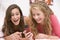 Teenage Girls Lying On Bed Using Mobile Phone