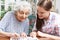 Teenage Granddaughter Helping Grandmother With Crossword Puzzle