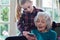 Teenage Granddaughter Showing Grandmother How To Use Mobile Phone