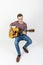 Teenage guitar player sits on a chair and plays western guitar