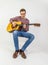 Teenage guitar player sits on a chair and plays western guitar