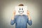 Teenage guy covering face using a white paper sheet with smiling emoticon sketch, like fake mask for hiding identity and real