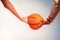 Teenage hands with bunch of bright bracelets holding basketball ball