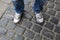 Teenage legs in sneakers and blue jeans standing on paving stones