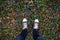 Teenage legs in sneakers on springtime ground with blue flowers