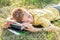 Teenage lying and sleeping on the grass with book.