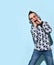 Teenage male in sunglasses and hood, blue jeans and stylish hoodie, black bracelet. Calling someone, posing on blue background