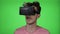 Teenage man experiencing for the first time an amazing experience of virtual reality wearing VR headset gadget on green screen -