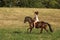 Teenage pretty girl on pony without saddle galloping on meadow in hot summer afternoon