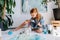 Teenage redhead girl is painting with brush on big canvas on floor in a workshop