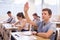 Teenage schoolboy raising hand to answer during lesson