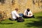 Teenage schoolboys sittin on grass working.