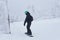 Teenage snowboarder going to slide down a mountain along a forest trail in frosty weather